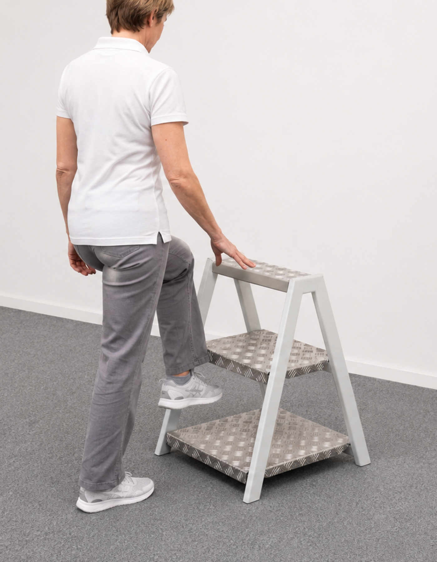 Patientin steigt beim Gleichgewichtstraining auf den WorkPark Multitritt WP 07
